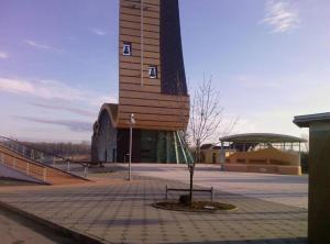 a building with a tower with a tree in front of it at Rooms Zeko in Aljmaš