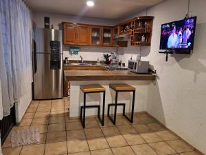 a kitchen with a refrigerator and two bar stools at Casa Ana Victoria in Morelia