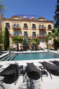 une piscine avec des chaises et un bâtiment dans l'établissement GOLDEN TULIP CANNES HOTEL de PARIS, à Cannes