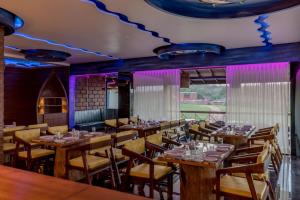 a dining room with wooden tables and chairs at Dio Regaalo Theme Resort, Ratnagiri in Ratnagiri