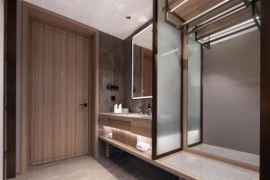 長沙市にあるMEHOOD LESTIE HOTEL- Changsha South Sation Branchの洗面台と木製のドアのあるバスルーム +40枚の写真