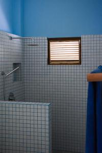 a white tiled bathroom with a shower and a window at Nova Surf House in Matara