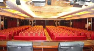 an empty auditorium with red chairs and a stage at Lavande Hotels· Yueyang Linxiang Zhongfa in Linxiang