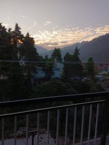 Una vista de una puesta de sol desde un balcón con árboles. en Ruk bae cafe restro & hotel, en Mussoorie