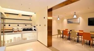 City Comfort Inn Kunming High Speed Railway South Station Yongxin Harvard في كونمينغ: مطبخ وغرفة طعام مع طاولة وكراسي