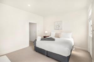 une chambre blanche avec un grand lit et une table dans l'établissement Hurst Cottage North Hobart x 6, à Hobart