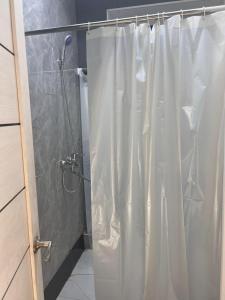 a shower with a white shower curtain in a bathroom at Lighthouse in Aktau