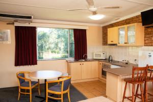 a kitchen with a table and a table and chairs at Nandewar Motor Inn in Narrabri