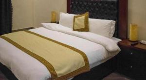 ラホールにあるHotel Grand Millenniumの白いシーツと枕が付いた大きなベッドのある寝室