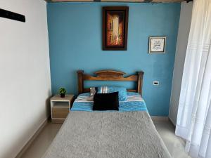 une chambre avec un lit avec un mur bleu dans l'établissement Tranquilo y bonito, à Bogotá