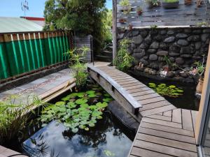 a garden with a wooden bridge over a pond with lilies at Maeva Sunset View in Punaauia