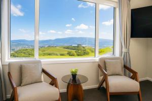 a room with two chairs and a table and a large window at Hilltop Ocean Hideaway - Aotea Wellington in Porirua