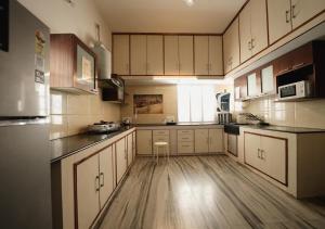 a kitchen with white cabinets and a wooden floor at Palace Hostel by Borrbo in Mysore