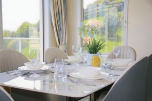 a white table with glasses and plates on it at Hilltop Ocean Hideaway - Aotea Wellington in Porirua