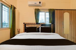 a bedroom with a large bed with green curtains at Super Hotel O Birsa Athletics Stadium Formerly De Anmol Suites in Nāmkom
