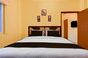 a bedroom with a large bed and two chairs at Super Hotel O Birsa Athletics Stadium Formerly De Anmol Suites in Nāmkom +22 photos