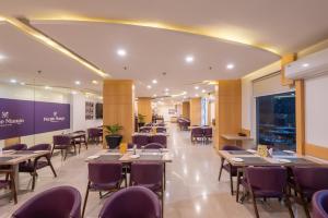 a dining room with tables and purple chairs at Mango Grove Hotel in Chandīgarh