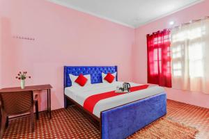 ein Schlafzimmer mit einem blau-roten Bett und einem Tisch in der Unterkunft Hotel O ADORA STAY in Bheta