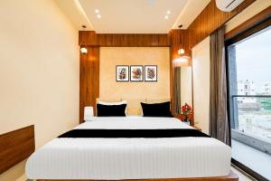 a bedroom with a large white bed and a window at Super Townhouse GIDC Bol Sanand in Ahmedabad +35 photos