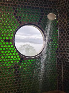 een douche met een rond raam in een groene badkamer bij Community Lodge Nepal - Chhimeki Lodge in Nagarkot