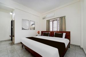 a bedroom with a large bed and a window at Super Hotel O Pathanamthitta Near Mahatma Gandhi Statue in Pathanāmthitta