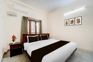 a bedroom with a black and white bed and a window at Super Hotel O Pathanamthitta Near Mahatma Gandhi Statue in Pathanāmthitta