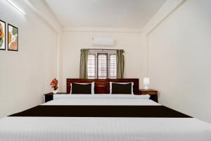 a bedroom with a large bed and a window at Super Hotel O Pathanamthitta Near Mahatma Gandhi Statue in Pathanāmthitta
