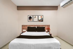 a bedroom with a large white bed with two pictures on the wall at Super Collection O Palampur Surat Formerly Hotel Royal Paradise in Bhatha