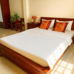 a bedroom with a large bed with orange pillows at Gia Hoang Hotel in Quy Nhon