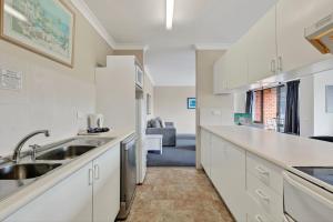 a kitchen with white cabinets and a sink at Coastal Haven Sandcastles 220 in Coffs Harbour