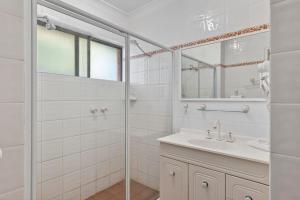 a white bathroom with a sink and a shower at Coastal Haven Sandcastles 220 in Coffs Harbour
