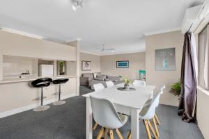 a dining room and living room with a white table and chairs at Coastal Haven Sandcastles 220 in Coffs Harbour