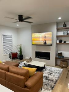a living room with a couch and a tv on the wall at Downtown New 3 Story Sleeps 14 in Baton Rouge