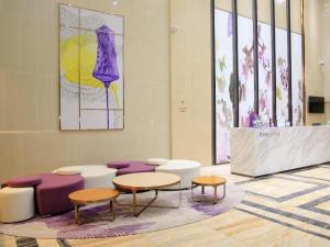 MaomingにあるLavande Hotel Maoming High-speed Railway Station Xinfu Roadのテーブルと椅子、絵画が飾られた部屋