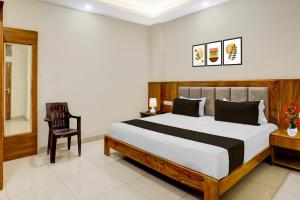 a bedroom with a large bed and a chair at Super Townhouse Varanasi City Station Formerly S Kumar Inn in Varanasi