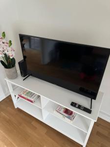 TV de pantalla plana en un centro de entretenimiento blanco en Your Twickenham Nest Near The Stadium, en Twickenham