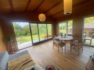 a living room with a table and chairs and windows at Romantic Retreat Close To The Beach in Fårevejle