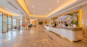 a lobby of a hotel with two people at a counter at Vienna Hotel Chongqing West Station Square in Chongqing