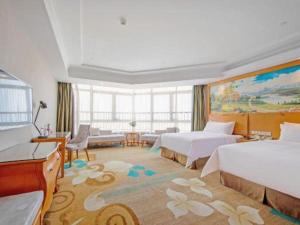 中山市にあるVienna Hotel Guangdong Zhongshan Ancient Town Haizhouのベッド2台とリビングルームがあるホテルの部屋