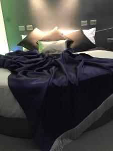 a bed with purple sheets and pillows on it at Hotel Tiro a Volo in Pozzuoli