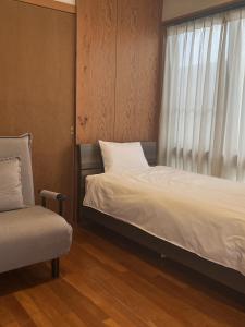 a bedroom with a bed and a chair and a window at お休み処おおはま in Yomitan +44 photos