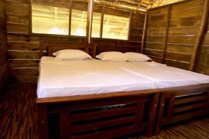 a large bed in a wooden room with two pillows at Nature Win Yala in Hambantota