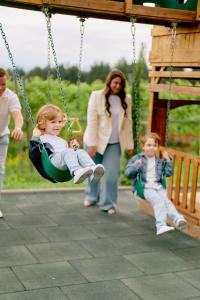 Uma mulher e crianças brincando em um balanço. em Panorama Kakheti Resort em Gurjaani
