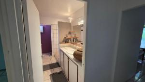 a white bathroom with a sink and a mirror at La Maison Plage et Sunset in Paeau