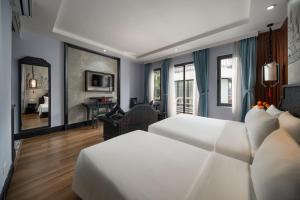 a bedroom with two beds and a living room at Hanoi Indochine Premium Hotel in Hanoi