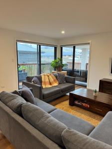 a living room with two couches and a table at Green Hill Views - Family Home close to Hobart - 4bed, 2bath in Rokeby +18 photos