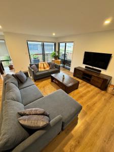 a living room with a couch and a flat screen tv at Green Hill Views - Family Home close to Hobart - 4bed, 2bath in Rokeby
