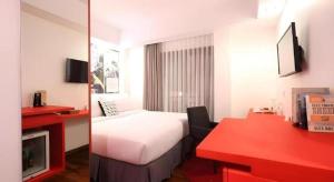 バンドンにあるThe Silk at Dago Boutique Hotelのベッドと赤いデスクが備わるホテルルームです。
