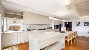 a kitchen with white cabinets and a large island at Pearl On The Beach By Holidayco in Umina