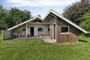 une petite maison en bois avec une terrasse dans un champ dans l'établissement Charming Cottage Near The Water, à Kisserup 8 autres photos